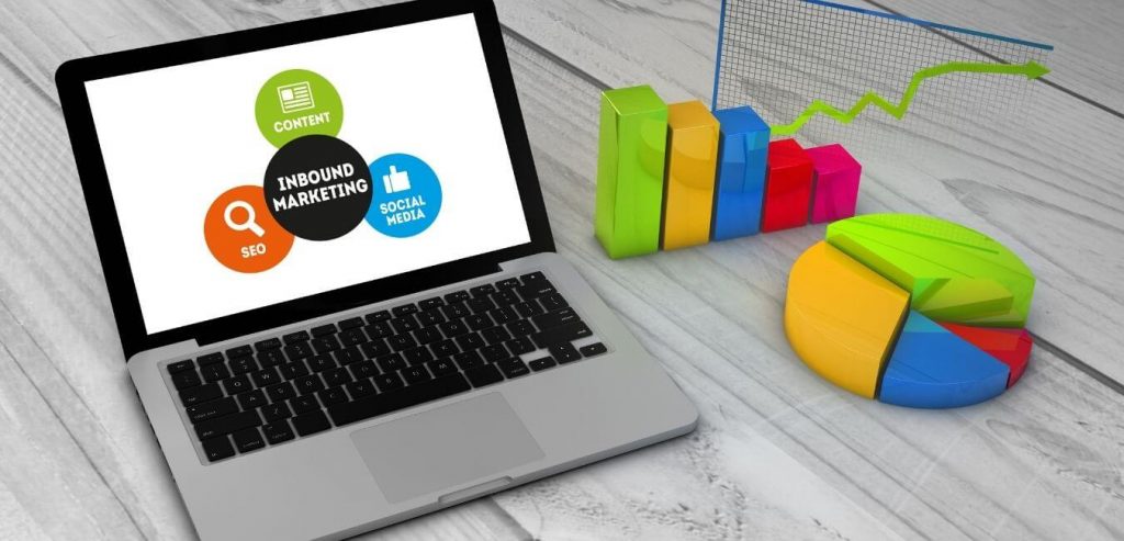 laptop with inbound marketing graphics on the screen and charts next to it