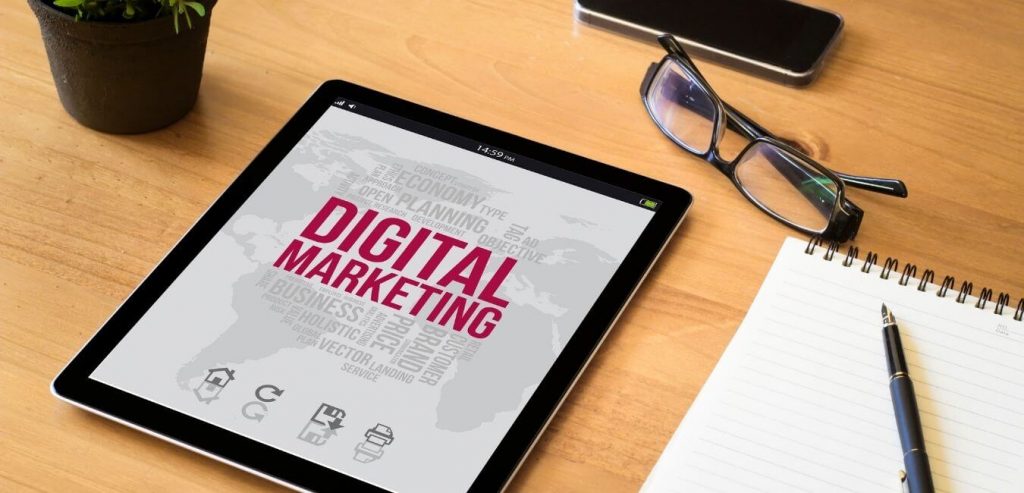 marketing your business with digital marketing in red on a white tablet screen, layoing on a desk