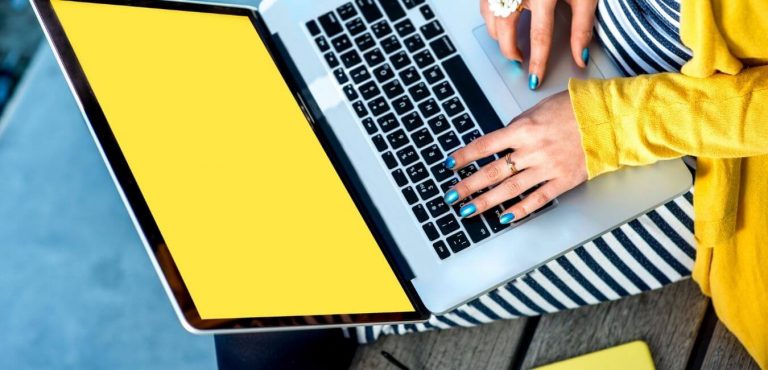 Person in a yellow jacket typing copywriting on their laptop
